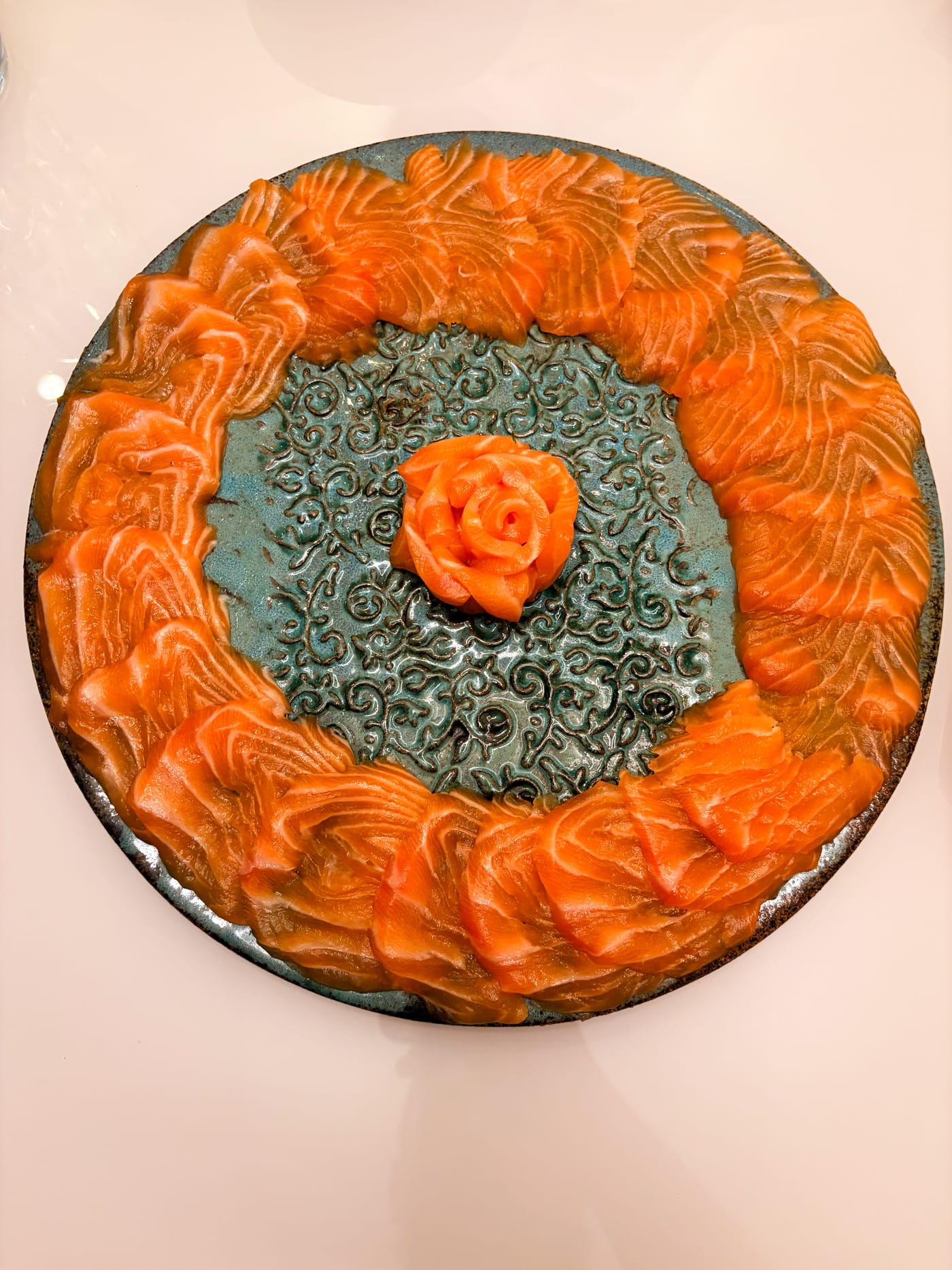 Sashimi de salmão disposto em círculo, com rosa de salmão ao centro